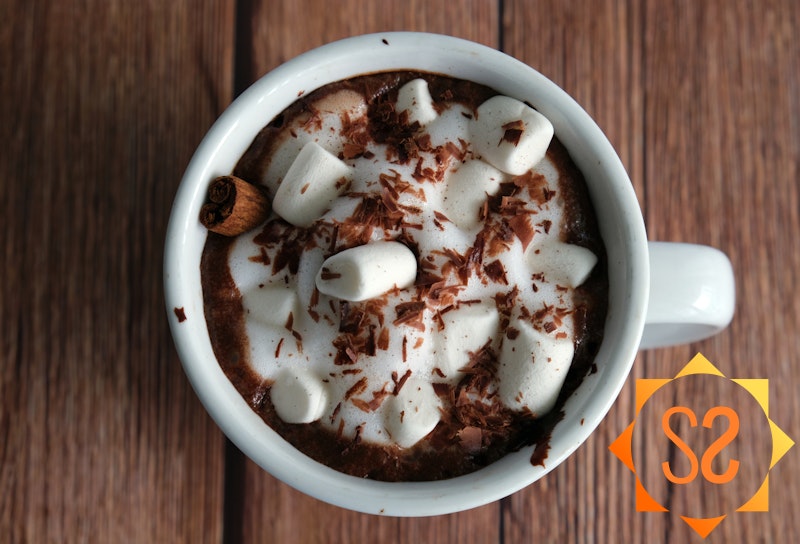 Foamy hot cacao with maca root topped with marshmallows, chocolate, and a cinnamon stick