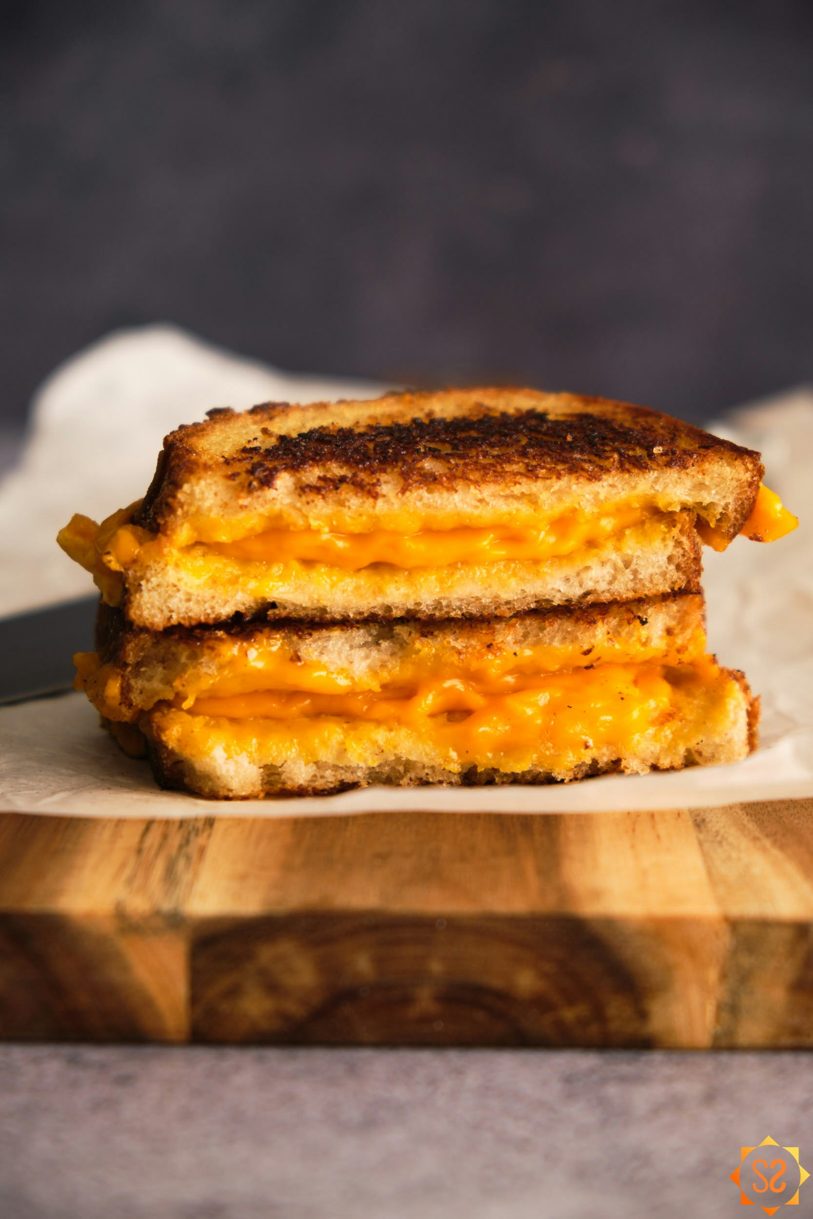 Side view of a Daiya grilled cheese sandwich, stacked, on a serving board