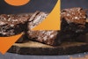 A close-up view of a brownie turned on its side, with stacks of brownies to the sides.