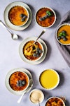 seven creme brulee dishes on a table, one with a spoon in it, another without the topping