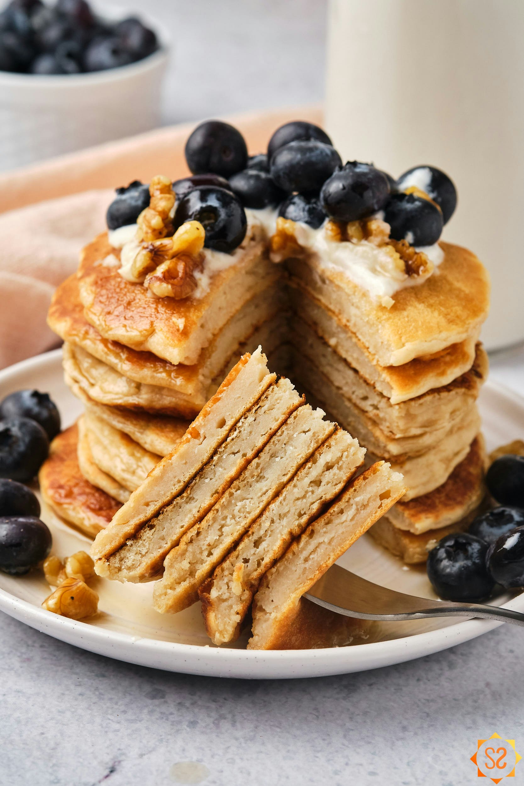 A stack of vegan protein pancakes next to cut pieces on a fork.