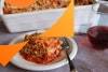 Lasagna piece on a plate with casserole in background