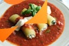 a side angle view of three vegan cannelloni on round plate with marinara sauce, vegan mascarpone sauce, and basil