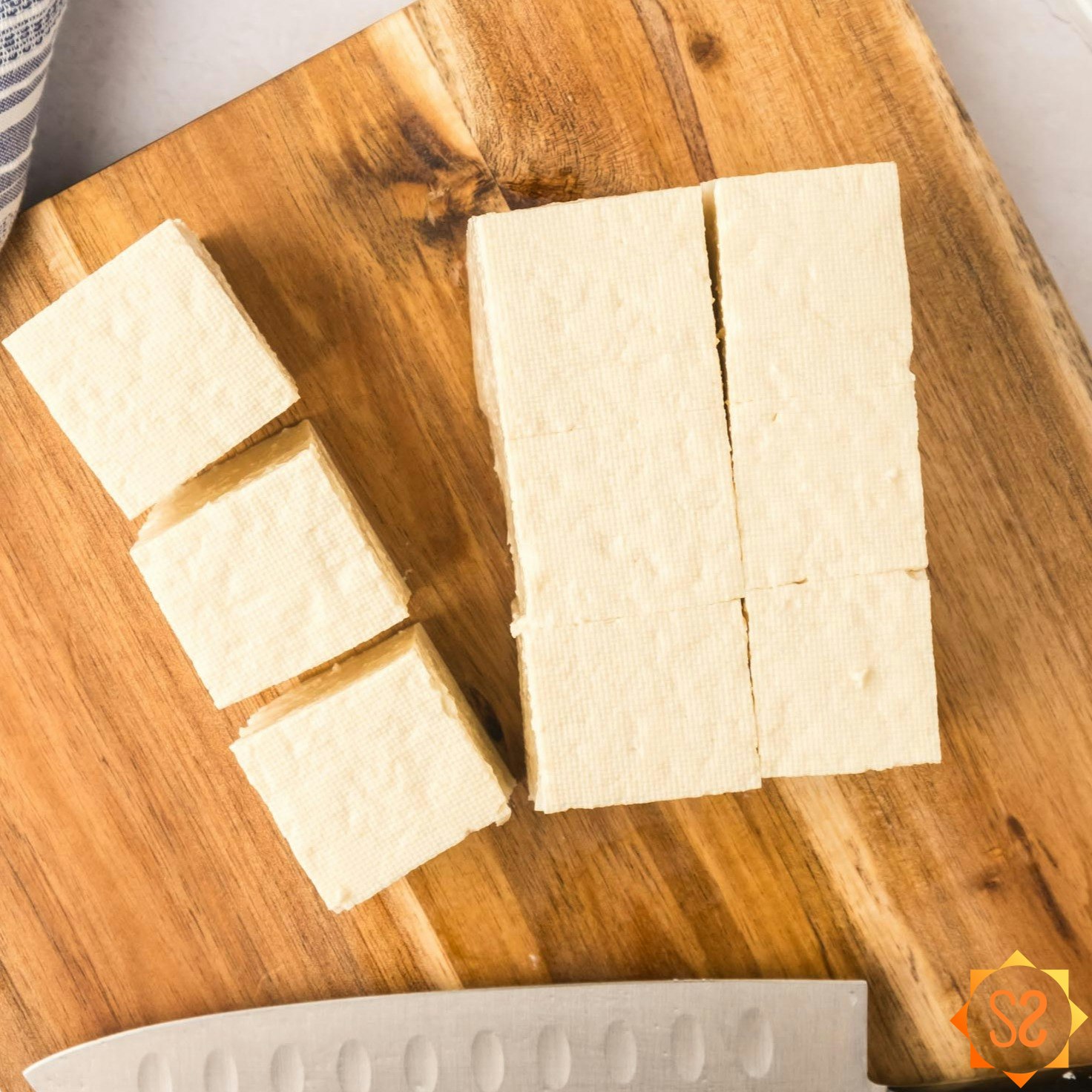 Tofu on a cutting board, chopped.