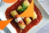 a top-down view of three vegan cannelloni on a square plate