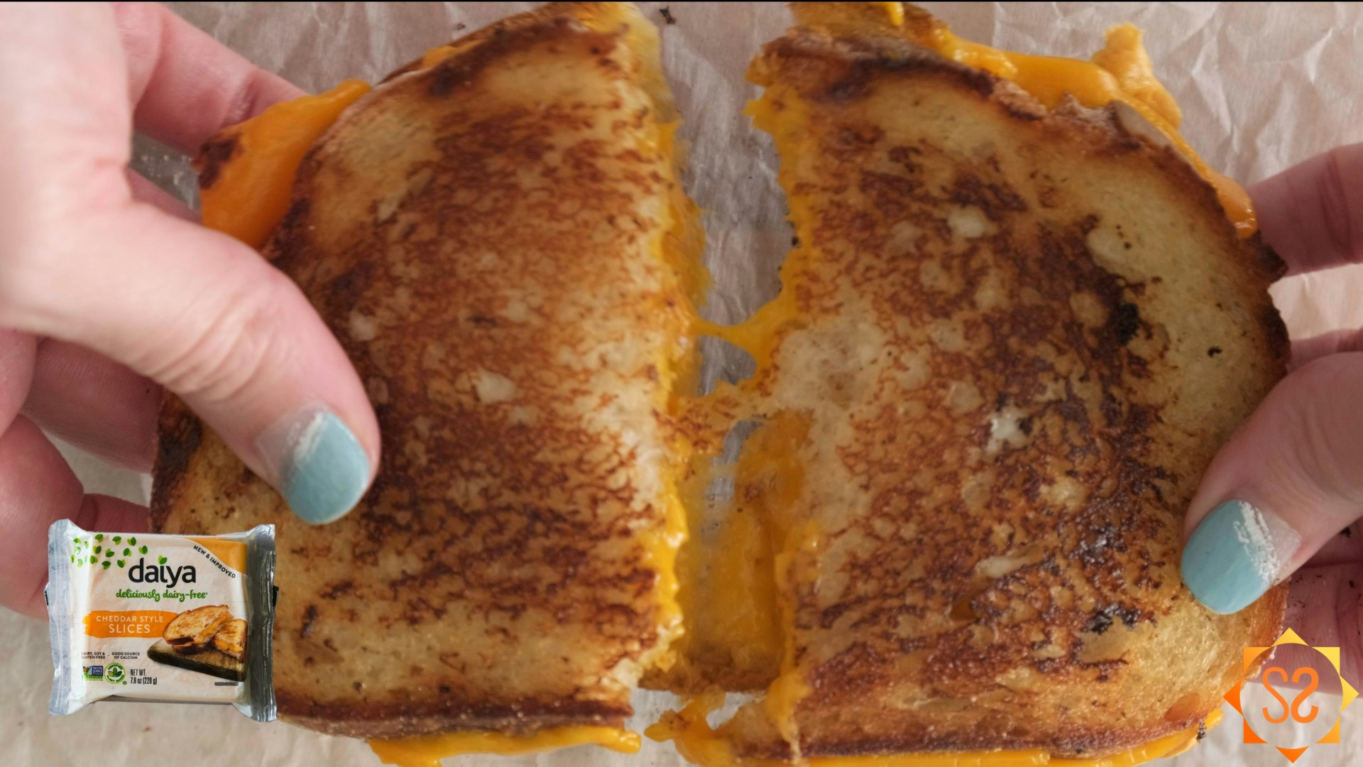Hands pulling apart a grilled cheese sandwich made with Daiya cheddar