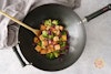 Tofu stir-fry in a wok with a wooden spoon
