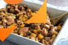 butternut squash stuffing in a casserole dish with a wooden spoon in the stuffing