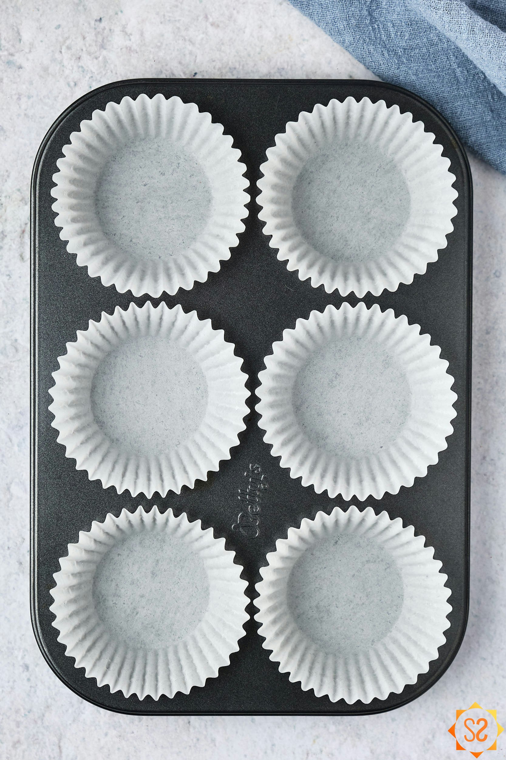 A 6-hole muffin tin filled with liners.