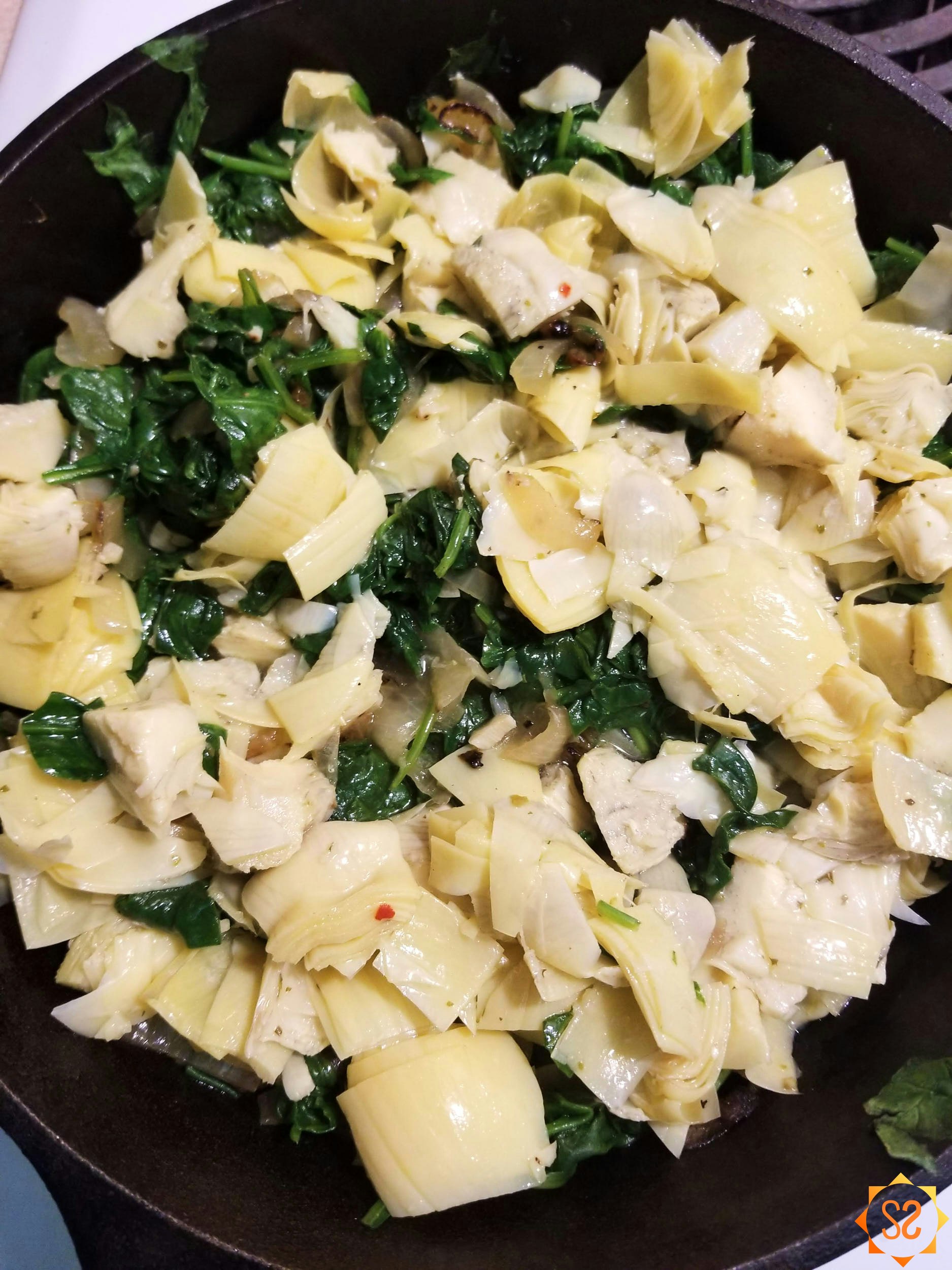 Onions, garlic, spinach, and artichokes in a pan