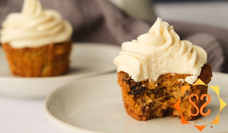 vegan carrot cake cupcake on a plate with a bite eaten
