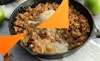 A close view of vegan apple crisp in a skillet with a scoop taken out.