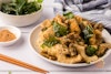 Fried oyster mushrooms on a plate with fried basil, seasoning powder, and chopsticks to the side.