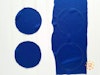 Two blue fabric circles next to a long piece of blue fabric with two circles drawn on it