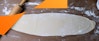 A wide view of the ravioli dough rolled on a floured surface with a rolling pin to the side