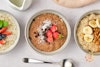 Three bowls of protein oatmeal, from left to right, chia berry, chocolate strawberry, and walnut banana.