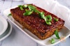 lentil loaf on a platter with basil on top, plates to the side