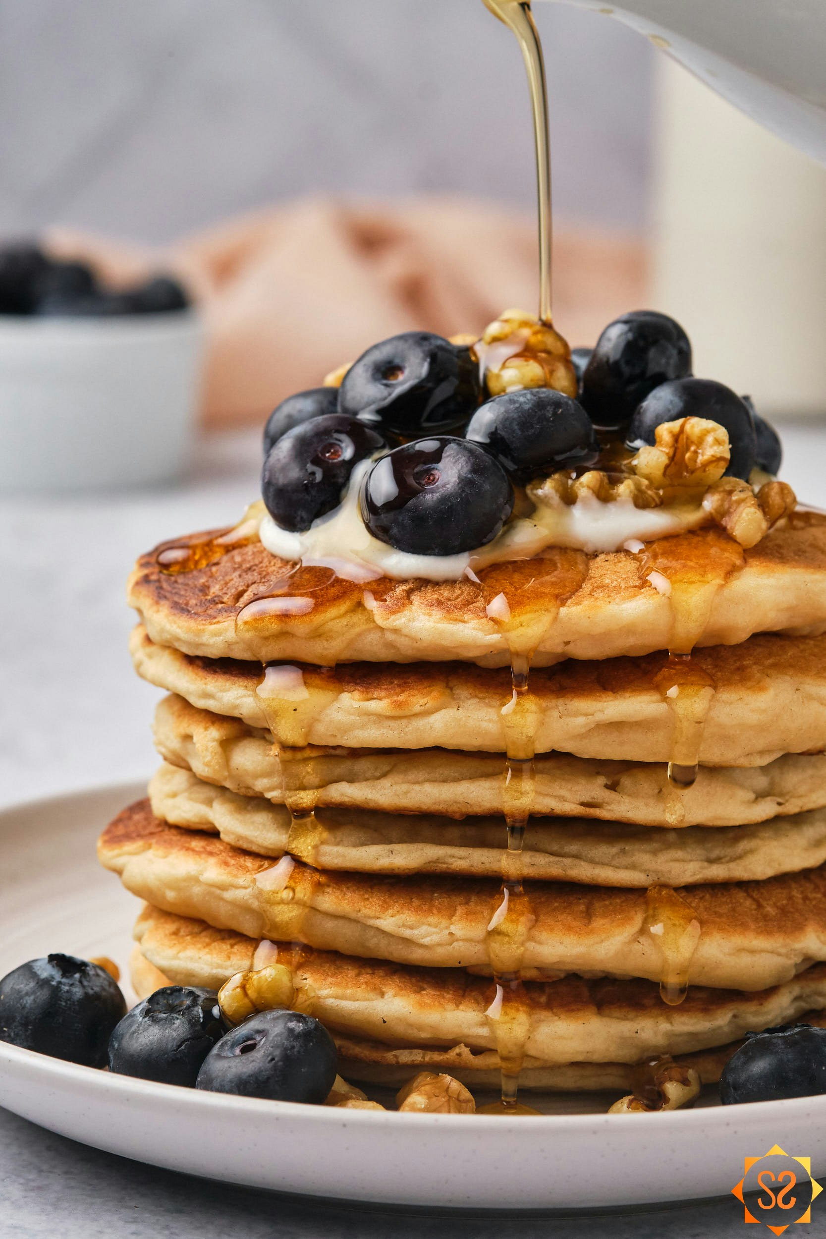 A close up view of a stack of vegan protein pancakes having maple syrup poured on top. 