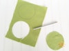 Yellow-green fabric with a circle cut out and another circle drawn on it.
