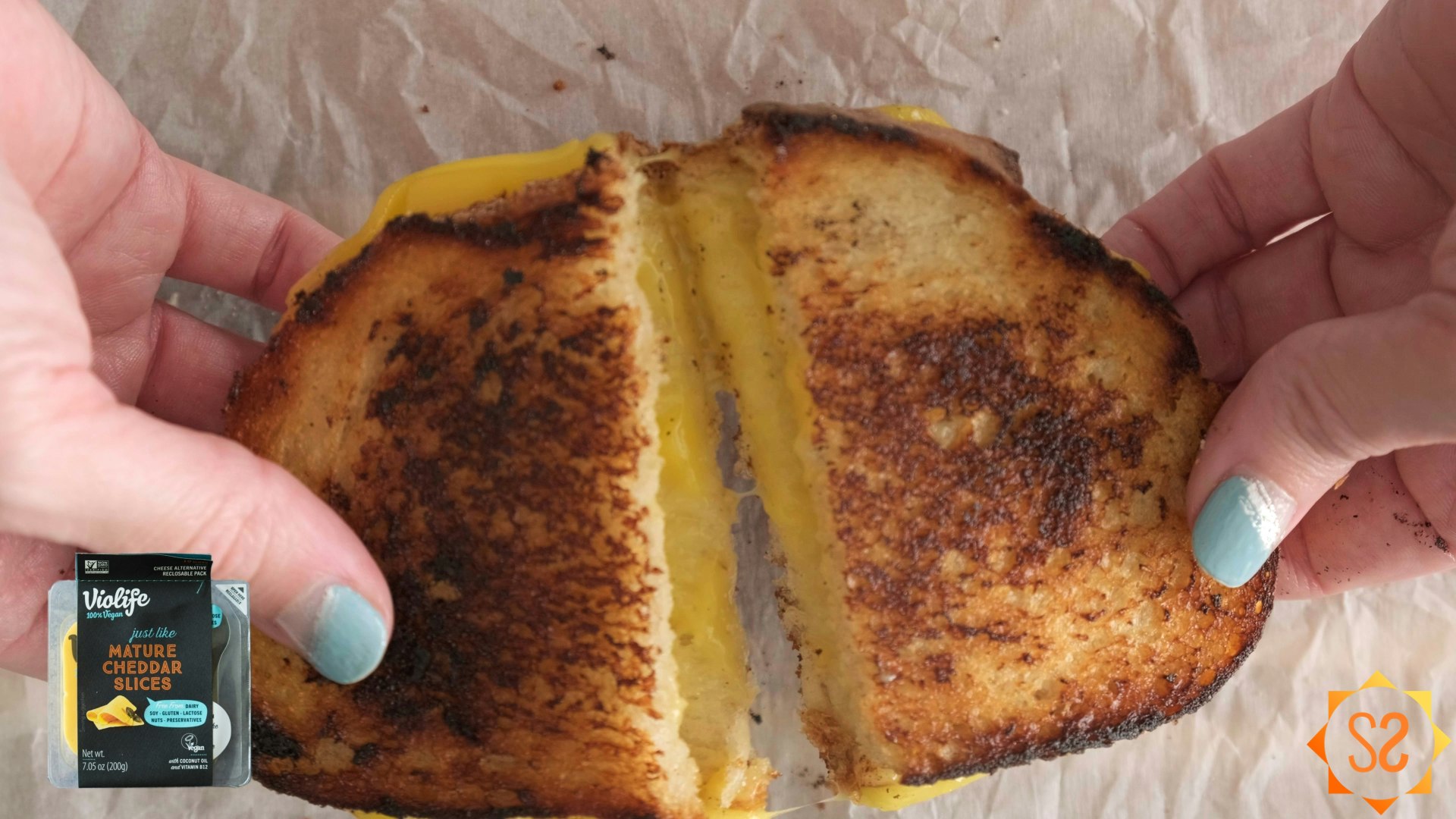 Two hands pulling apart a grilled cheese sandwich made with Violife Mature Cheddar