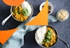 Two bowls of chickpea curry with a spice dish and cashews, overhead