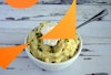 A bowl of vegan sour cream mashed potatoes with a spoon in it, chives and sour cream on top.