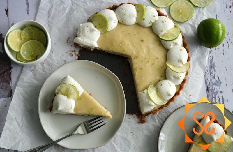 key lime pie slice on plate next to pie with lime slices