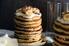 A vegan buttermilk pancake stack topped with whipped cream, bananas, and pecans.