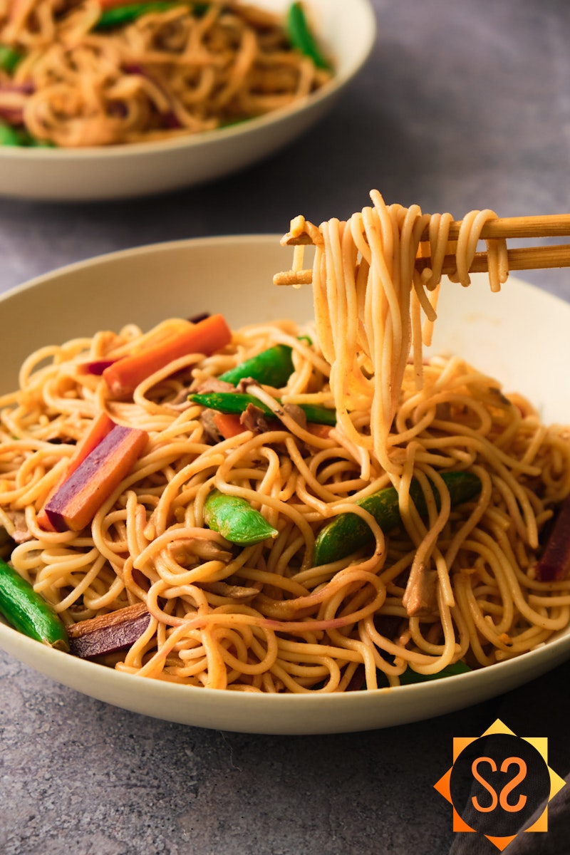 A bowl of noodle stir fry with chopsticks