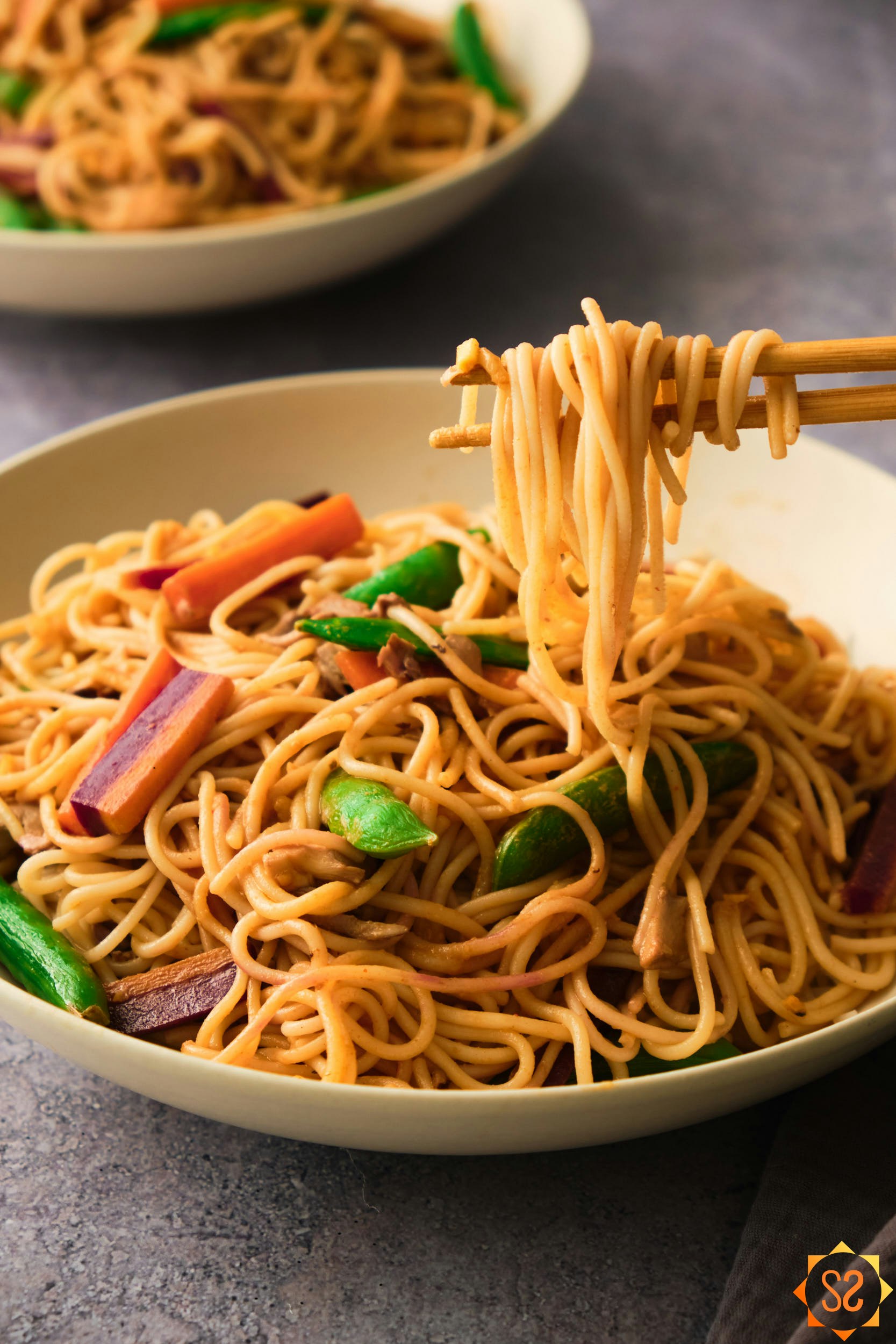 A bowl of noodle stir fry with chopsticks