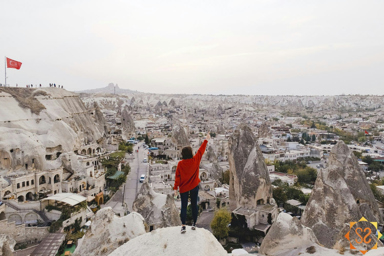 A person in a red jacket overlooking an old city in Turkey.
