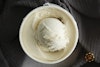 A top-down view of Oatly Vanilla Frozen Dessert in its package, with a scoop placed on top.