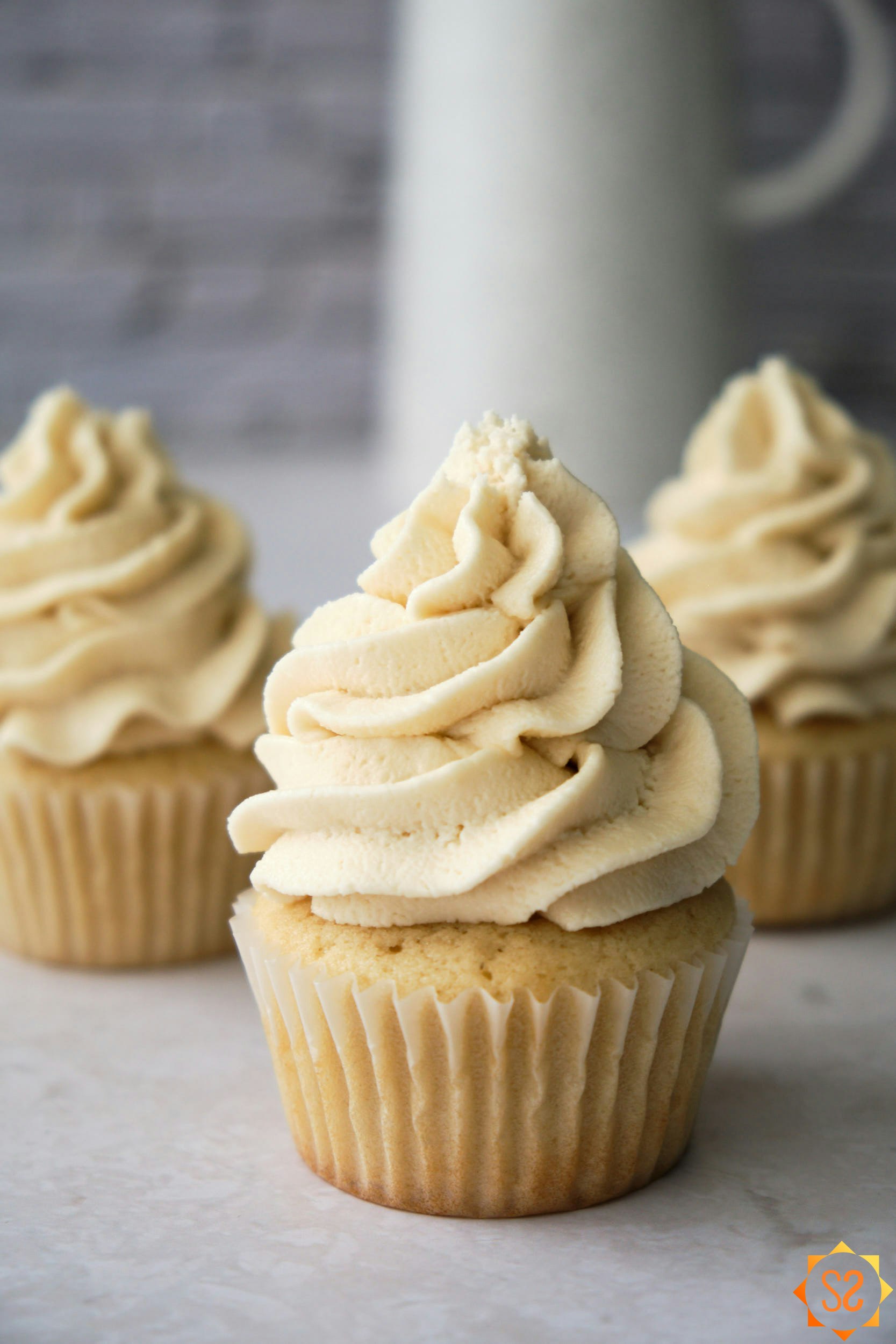 Three vanilla cupcakes topped with vegan buttercream frosting.