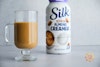 Silk Sweet & Creamy Almond Creamer mixed with coffee in a mug; the bottle of creamer is in the background
