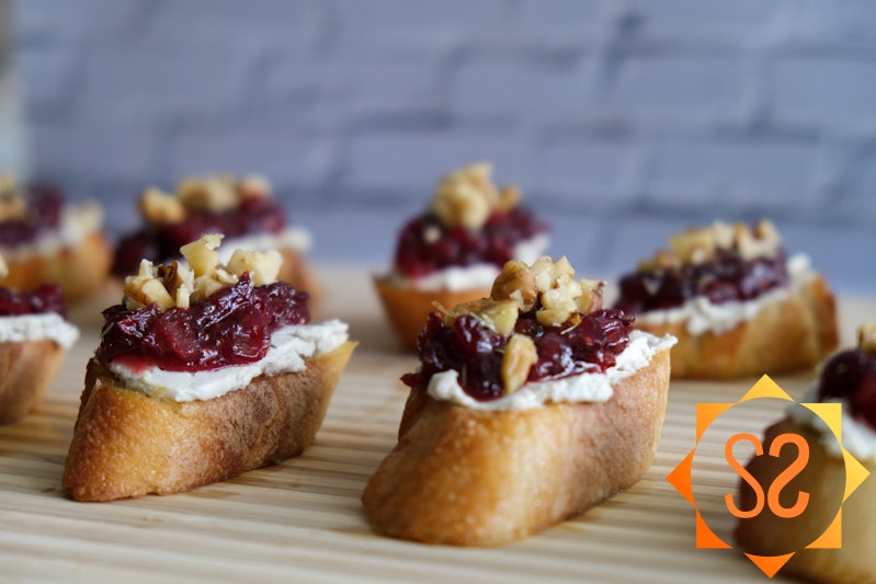 Cranberry and cashew cheese crostini on a cutting board
