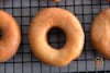 A close-up of vegan glazed donuts on a wire cooling rack
