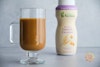 Good & Gather Sweet & Creamy Oatmilk Creamer mixed in with coffee in a mug, with the bottle in the background.