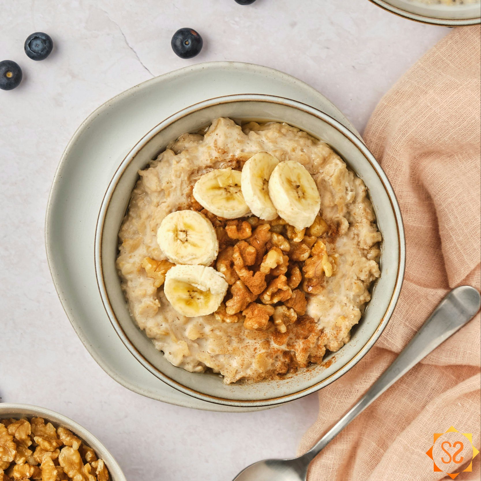 A top-down view of a bowl of high-protein oatmeal topped with bananas and walnuts.